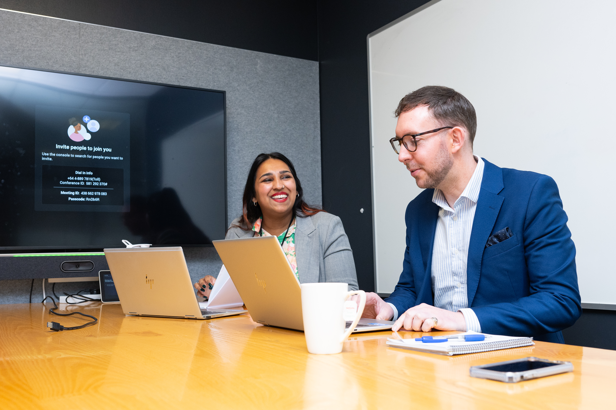 Two people sitting at a table together with laptops