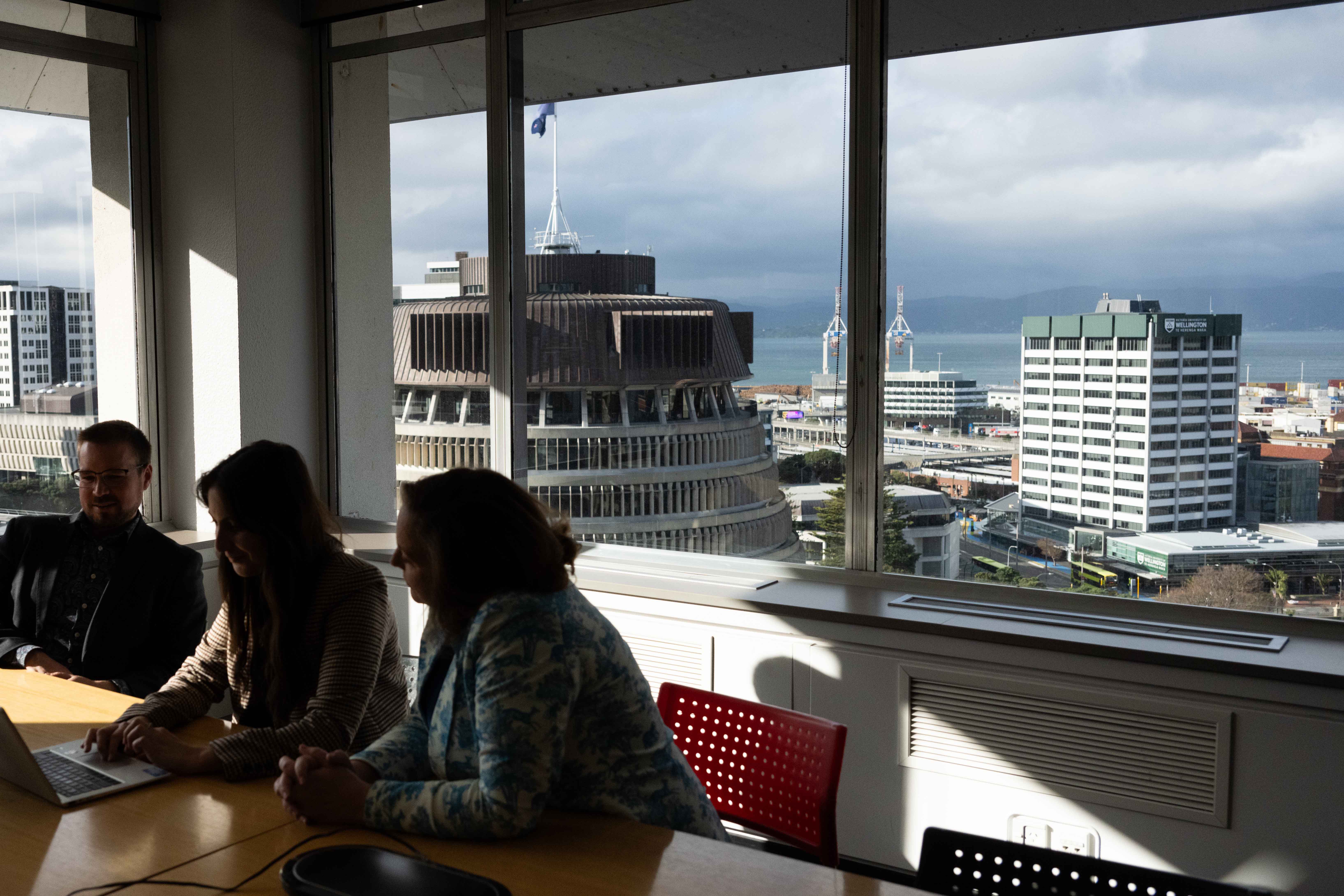 People sitting around a table next to a window with a city view